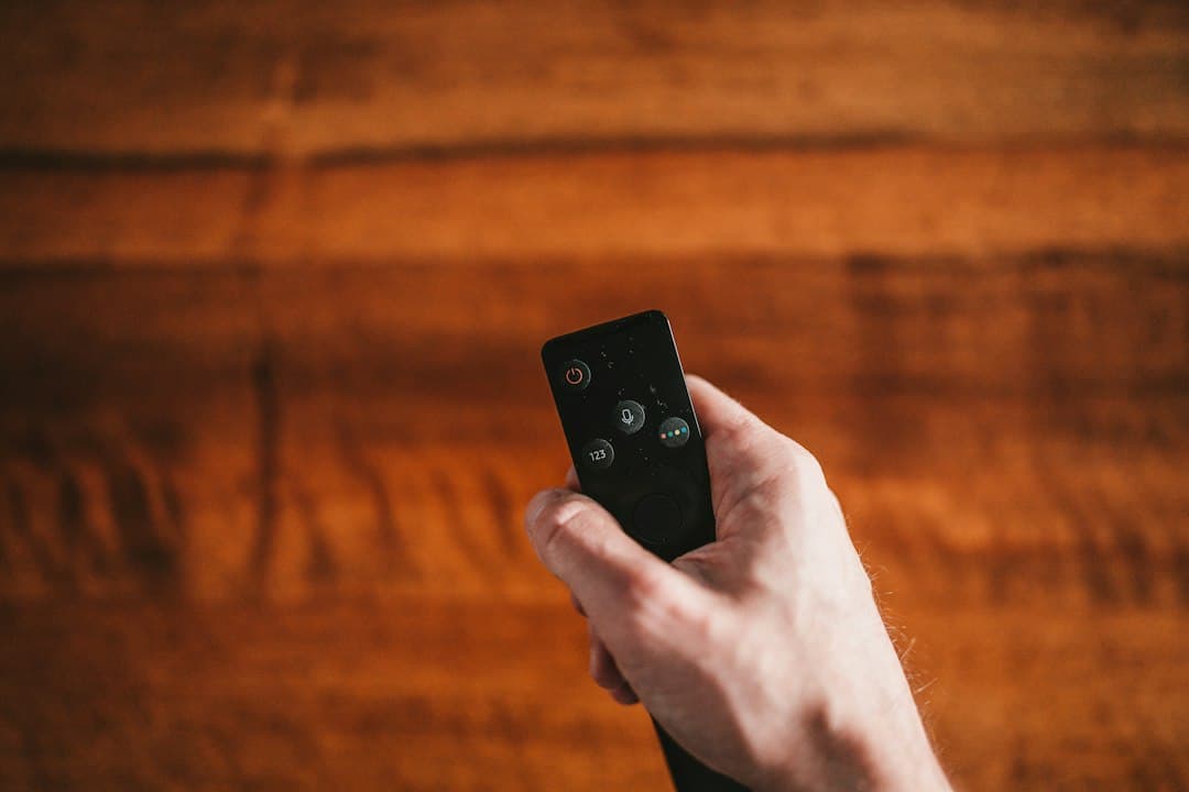 Hand pointing a small remote control, setting up Zyminex IPTV on a Fire TV Stick
